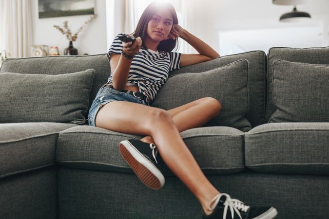 Young woman watching television sitting on couch at home