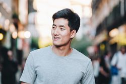 Confident Asian man walking along city street