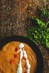 Orange cream soup and sliced carrot with green in bowls