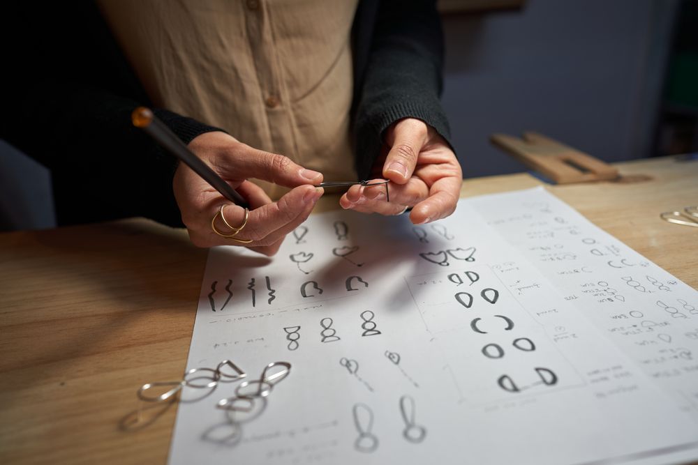 Faceless artisan with jewelry at table in workshop