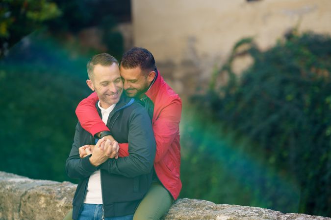 Cute male couple holding each other by the river, copy space
