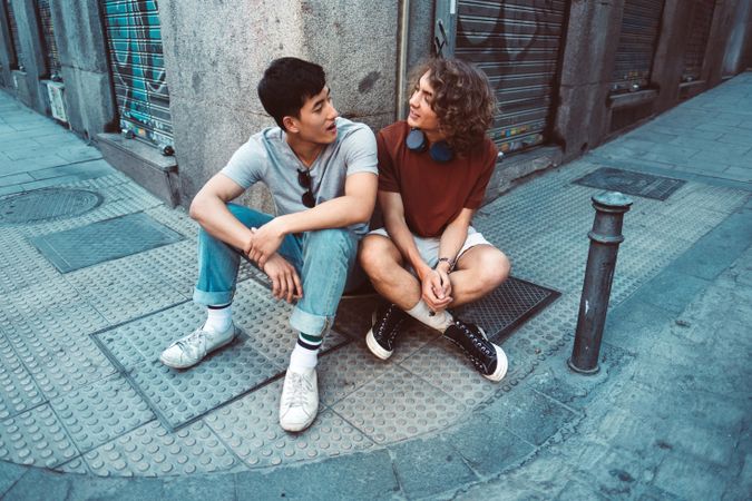 Relaxed multiracial male friends talking while resting by corner of building on street