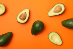 Ripe fresh avocado on orange background, top view