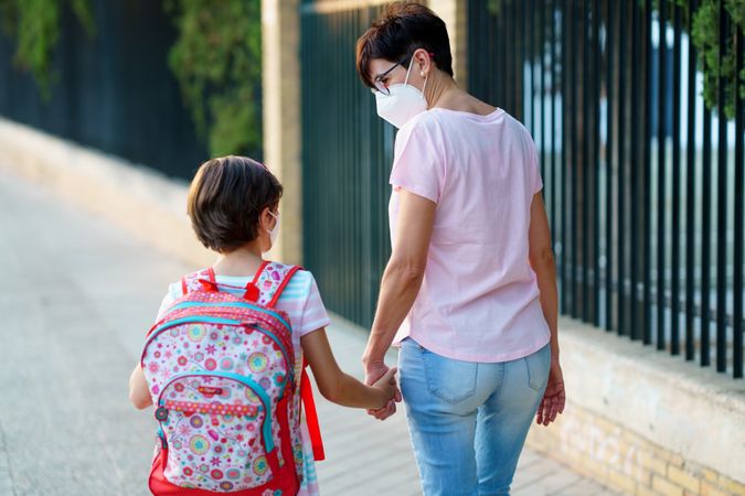 Mother and daughter walking to school in face masks