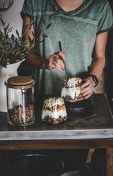 Woman eating yogurt parfait on rustic table