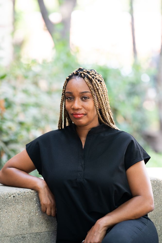 Portrait of heath care worker wearing black scrubs sitting on stone bench
