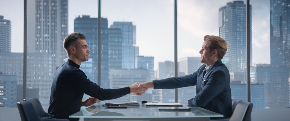 Two White Businessmen Sitting in Skyscraper Office and Signing Contract.