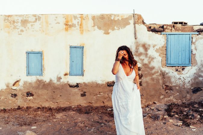 Woman in white dress walking out old house