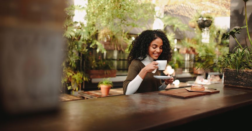 Smiling woman sitting at a table holding a coffee cup