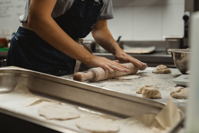 Baker rolling out dough in kitchen