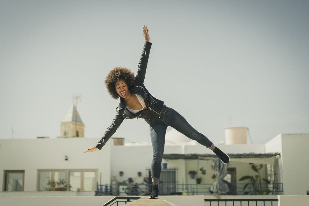 Funny Black woman balancing on wall