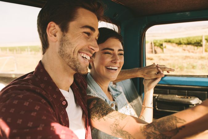 Smiling man sitting in truck with arm around woman during road trip