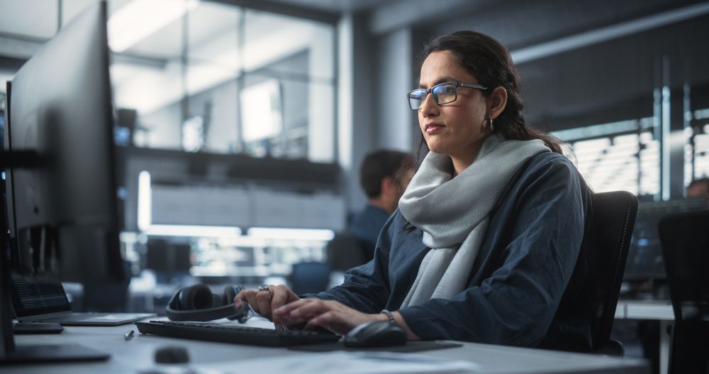 Portrait of a Thoughtful South Asian Engineer Working on Computer in a Technological Corporate Office.