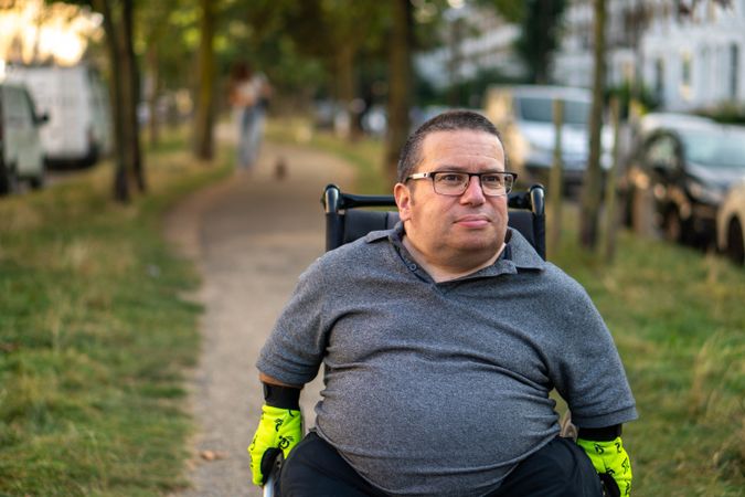 Portrait of happy man sitting in wheelchair in park path