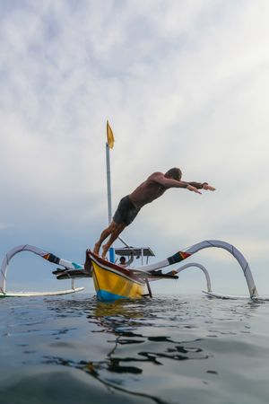 Man diving from boat in waving water