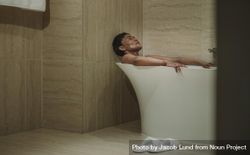 Woman lying in bathtub with her eyes closed 5qDxK0