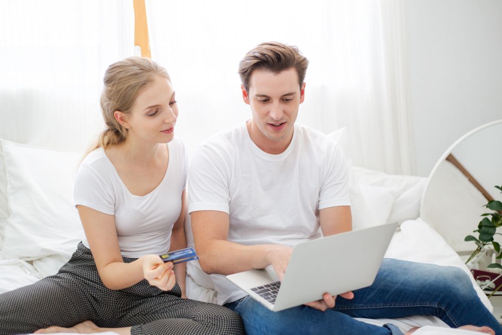 Young couple relaxing at home with laptop and credit card