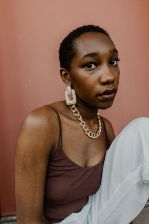 Woman in brown tank top wearing gold chain necklace and gold earrings