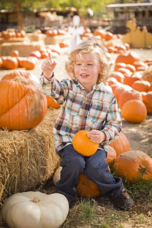 Boy Sitting and Holding His Pumpkin at Pumpkin Patch.