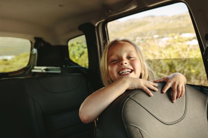 Smiling girl travelling by a car