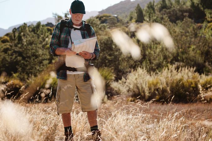 Mature man looking for the directions in a map while hiking