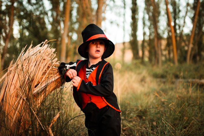 Boy in skeleton costume leaning on wood in the forest