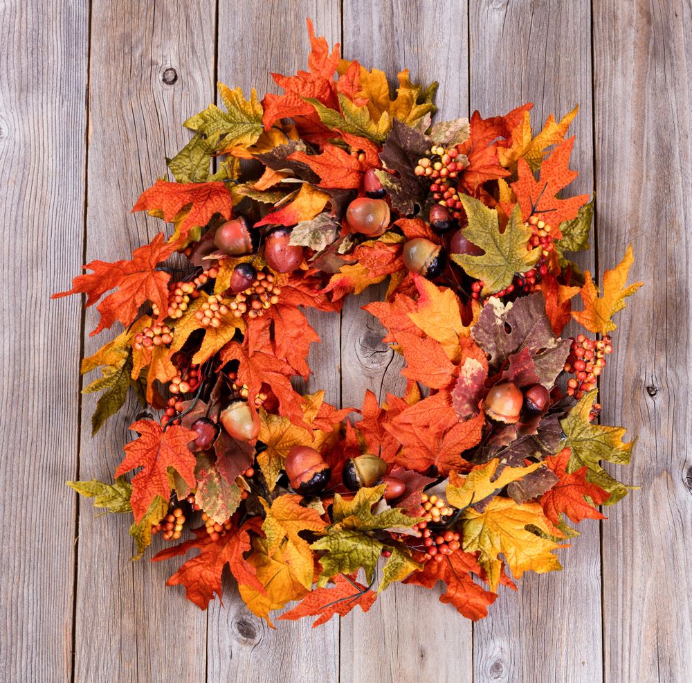 Wreath made of autumn leaves and acorns on rustic wood