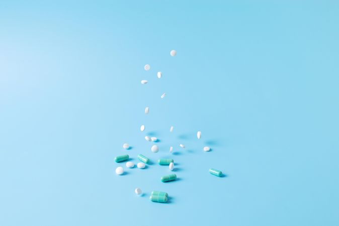 Variety of medications falling on blue backdrop