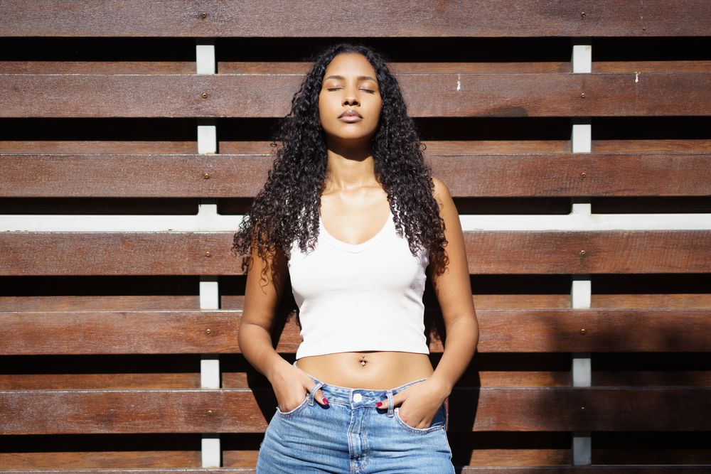 A Radiant Young Woman Posing Confidently and Gracefully Against a Charming Wooden Background