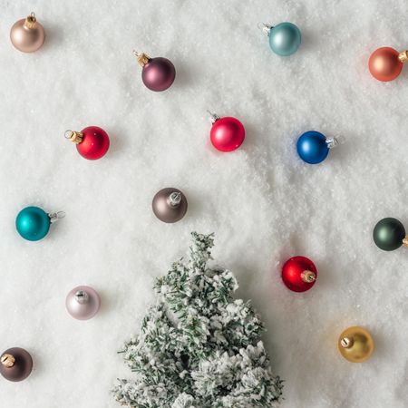 Miniature tree in snow with colorful Christmas baubles