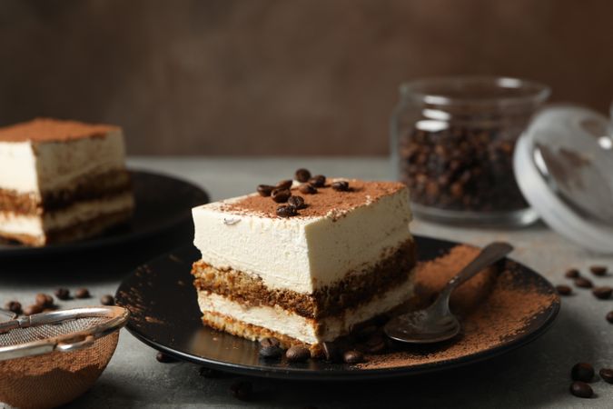 Composition with tasty tiramisu and coffee beans on gray background