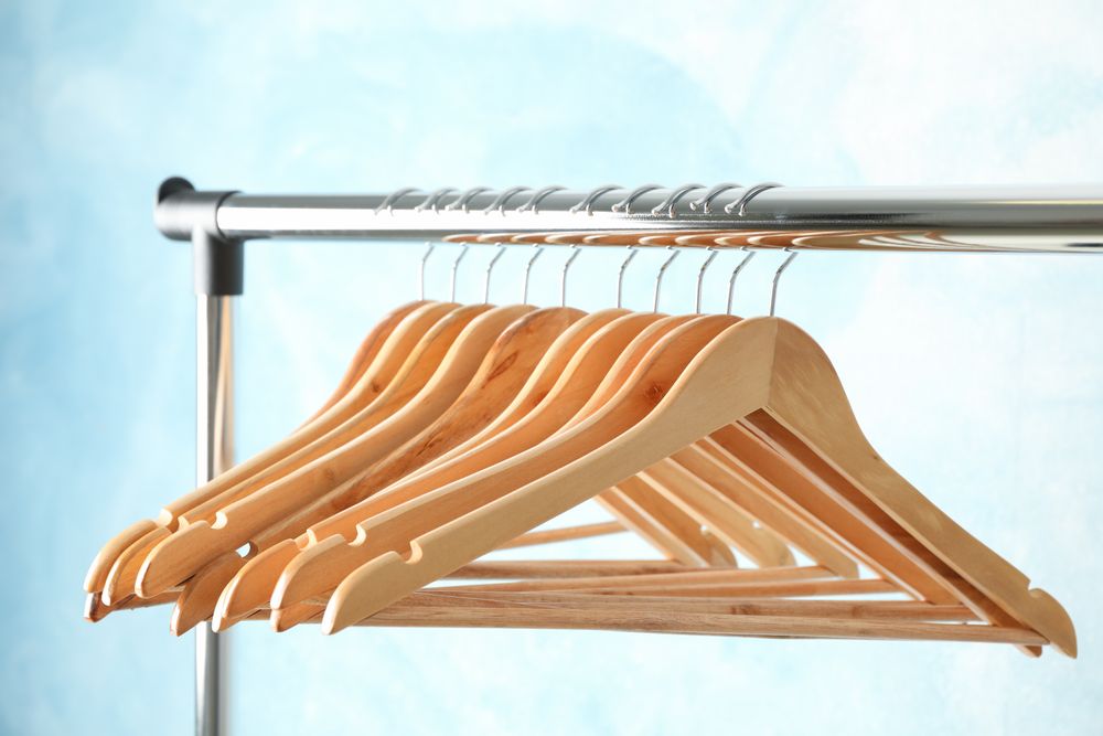 Hangers on rod against blue background, space for text