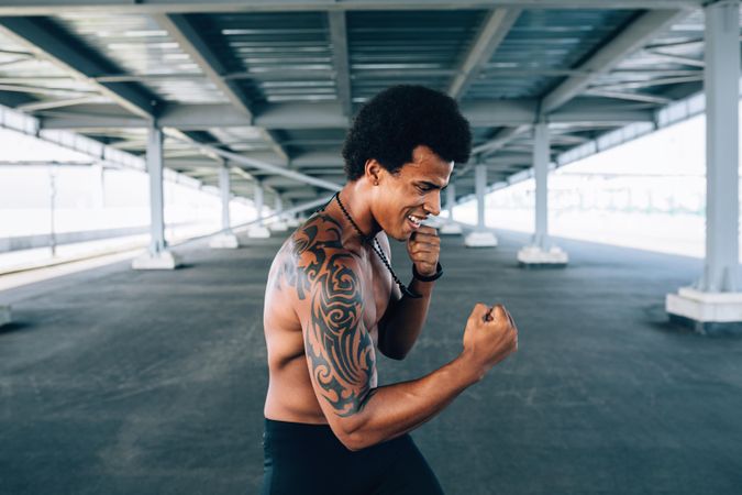 Smiling Black male athlete doing boxing training in underpass