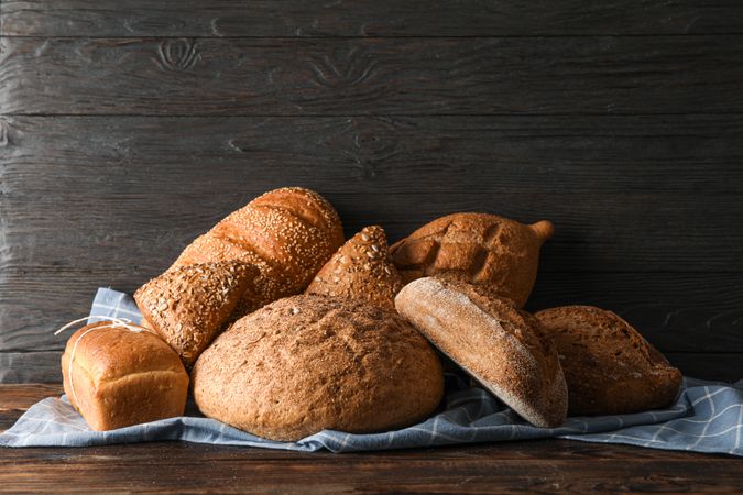 Bakery products on kitchen towel on wooden table against wood background, space for text