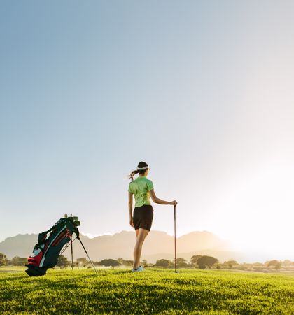 Athletic female golfer standing beside her golf bag