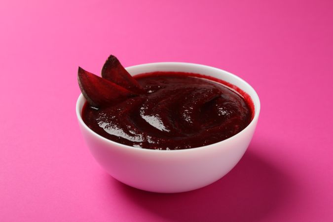 Bowl of borscht or beetroot soup on pink table