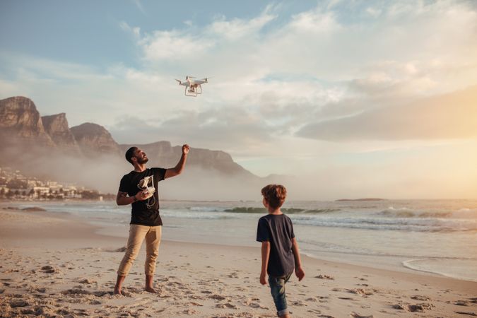 Father and son operating drone by remote control at the beach