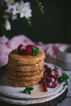 Pile of raspberry pancakes with honey on plate