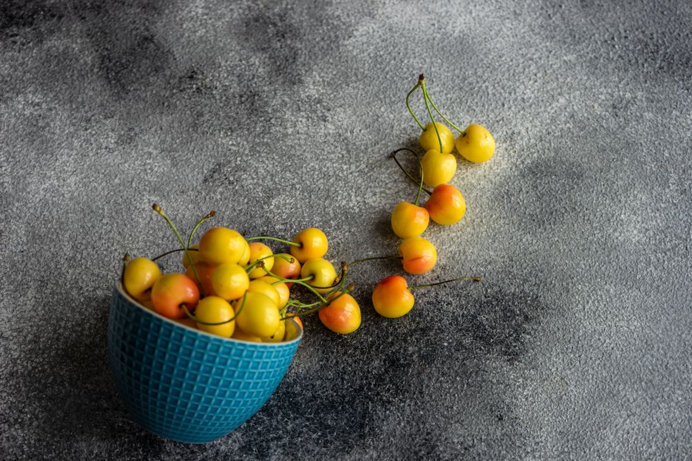 Yellow cherries spilling out of blue bowl