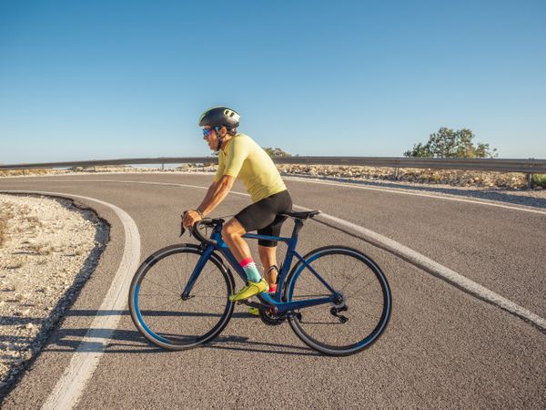 healthy man riding a bicycle on a mountain road in a sunny day