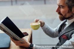 Smartly dressed man with coffee in cafe and book bGmGB5