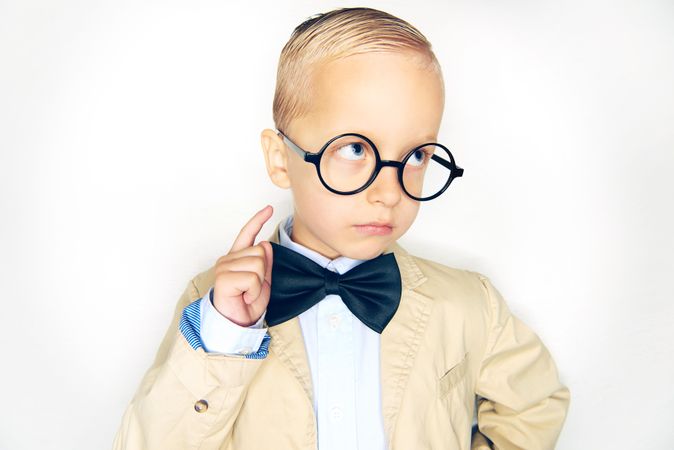 Blond boy making an moody face wearing round glasses and bow tie