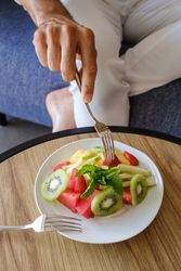 Crop man eating fruits at home