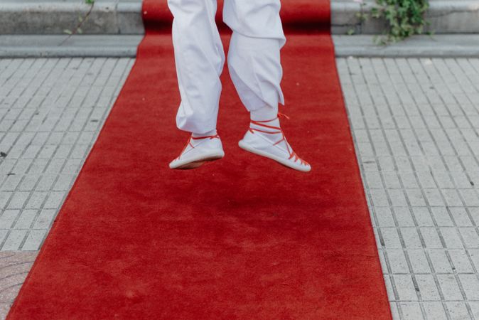 Person in gym shoes jumping on red carpet