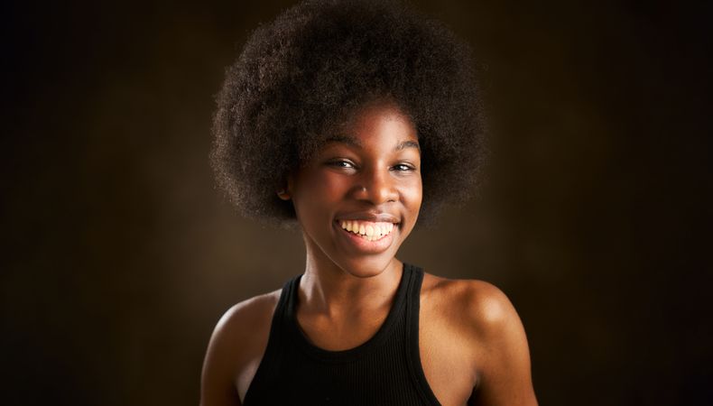Portrait of cheerful young Black woman in black vest