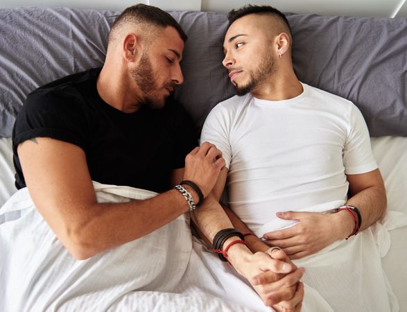 Smiling gay couple hugging on bed