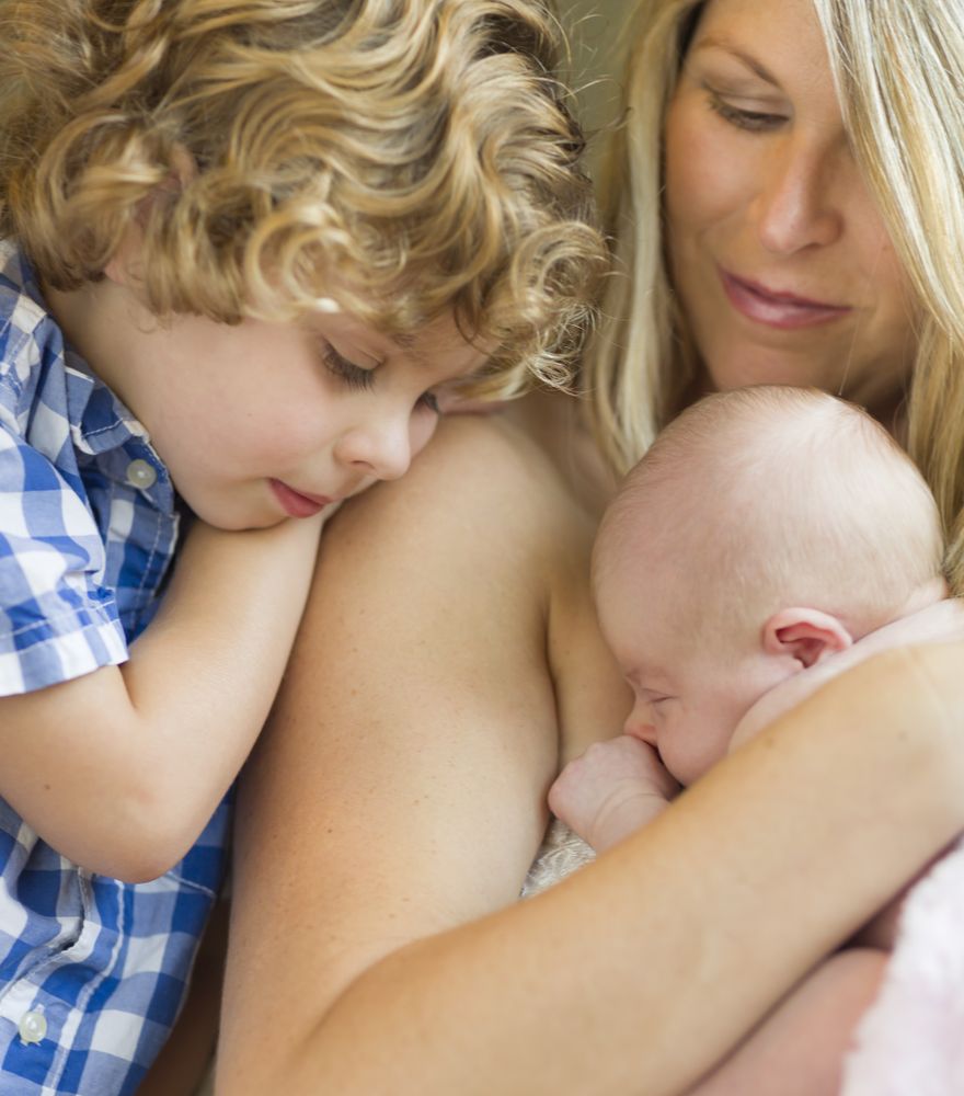 New Mother Holds Newborn Baby Girl as Brother Looks On