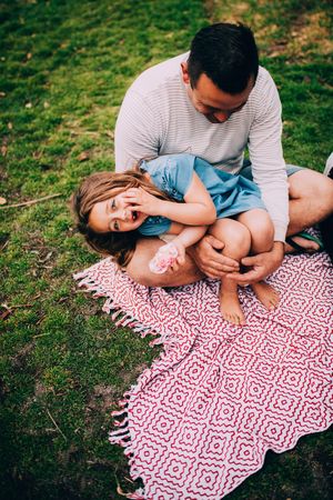 Daughter sits in father’s lap at the park