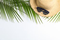 Composition with straw hat, sunglasses and palm leaves on light background. Top view, space for text