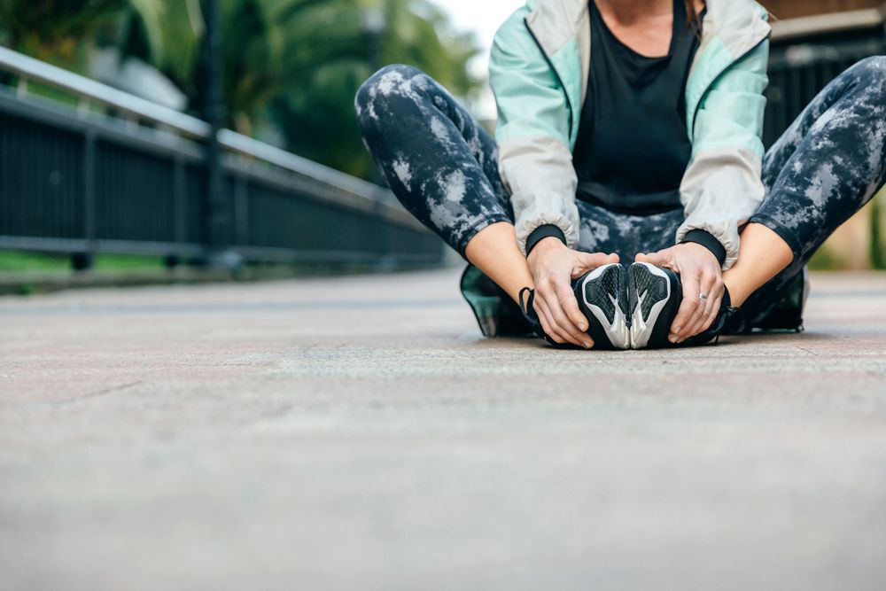 Woman stretching legs while sitting on the floor holding her feet with copy space